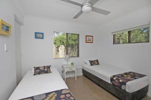 a bedroom with two beds and a ceiling fan at Red Door Beach House in Marcoola