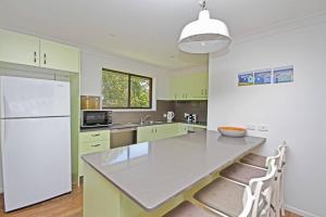 a kitchen with green cabinets and a white refrigerator at Red Door Beach House in Marcoola