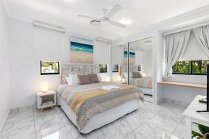 een witte slaapkamer met een bed en 2 ramen bij Unit 8 Bronte of Coolum in Coolum Beach