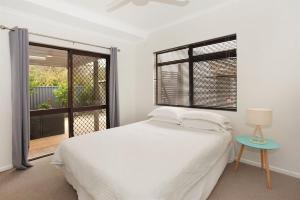 a white bedroom with a bed and a window at 6 Petrie Avenue in Marcoola