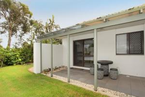 a white house with a patio with a table at 6 Petrie Avenue in Marcoola