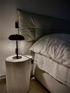 una cama con una lámpara negra en una mesa lateral en no.21house. Α Beach house in Rio,Patras, en Río