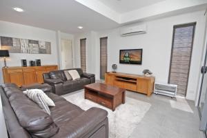 a living room with a leather couch and a table at 48 Boardrider Crescent in Marcoola