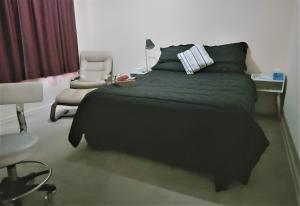 a bedroom with a black bed and a chair at 2BR house in West Lamington in Kalgoorlie