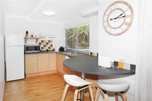 a kitchen with a table and a clock on the wall at Unit 13 Seacove Resort in Coolum Beach +4 photos