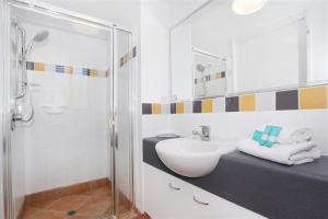 a white bathroom with a sink and a shower at Unit 13 Seacove Resort in Coolum Beach