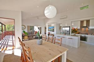 a kitchen and living room with a wooden table and chairs at Stunning Home With Spectacular Views in Coolum Beach