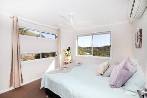 a white bedroom with a bed and two windows at Stunning Home With Spectacular Views in Coolum Beach