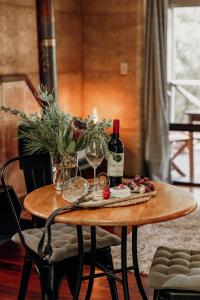 einen Holztisch mit zwei Flaschen Wein und Gläsern in der Unterkunft Balingup Jalbrook Cottages Jalbrook Estate in Balingup