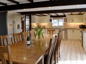 uma cozinha e sala de jantar com uma mesa de madeira e cadeiras em Cowslip - 23653 em Bradworthy