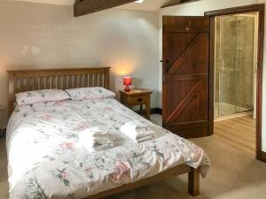 um quarto com uma cama com uma cabeceira de madeira e uma porta em Cowslip - 23653 em Bradworthy