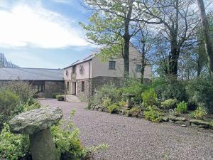 a stone building with a garden in front of it at Cowslip - 23653 in Bradworthy