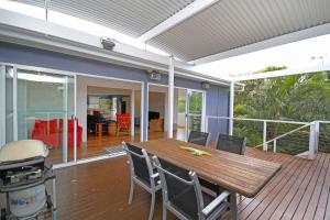 a patio with a wooden table and chairs on a deck at 25 Goongilla Street in Yaroomba