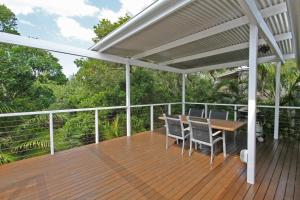 a wooden deck with a table and chairs on it at 25 Goongilla Street in Yaroomba