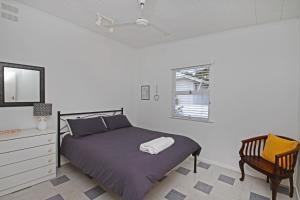 a bedroom with a bed and a chair and a window at 25 Goongilla Street in Yaroomba