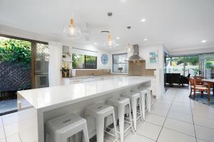 a kitchen with a large white counter and stools at 22 Sorrento Avenue in Coolum Beach