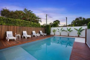 a swimming pool with chairs and a table and a fence at 22 Sorrento Avenue in Coolum Beach