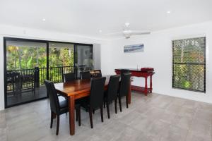 a dining room with a wooden table and black chairs at 8 Springfield Avenue in Coolum Beach
