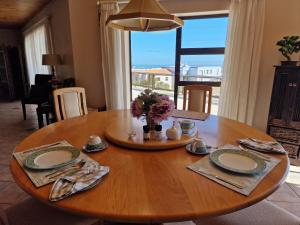 a wooden table with plates and a vase of flowers on it at Glenfinnan Guest House in Langebaan