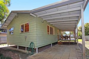 a green house with awning and a patio at 24 Sundew Street in Mudjimba