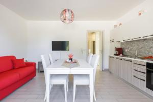 ein Wohnzimmer mit einem weißen Tisch und einem roten Sofa in der Unterkunft DELFINO - Ampio Appartamento a 40 metri dalla Spiaggia in Lido Conchiglia