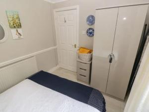 a small bedroom with a bed and a refrigerator at Clover Cottage in Haverfordwest