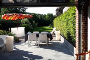 a patio with a table and chairs and an umbrella at B&B -La Grange in Bouvines