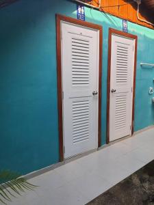 2 portes blanches sur un bâtiment bleu dans l'établissement Ban Tidlay - SHA, à Ko Yao Noi