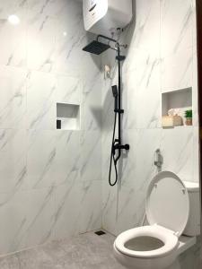 a white bathroom with a toilet and a shower at Davyn's House - Cozy and Private House in Lombok in Prampuan
