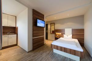 ein Schlafzimmer mit einem Bett und einem TV an der Wand in der Unterkunft Central Hotel-Apart München in München