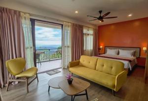 a bedroom with a bed and a couch and a balcony at Kokol Haven Resort in Kota Kinabalu