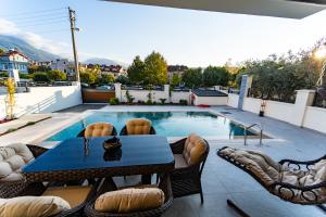 a patio with a table and chairs and a swimming pool at merkezde 8 kişilik özel havuzlu villa in Fethiye