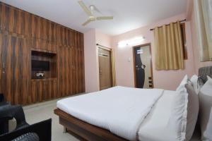 a bedroom with a white bed and a tv at Shreenath JI inn in Udaipur