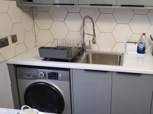 a kitchen with a sink and a washing machine at The Navarone Blue Orchid Flat in London