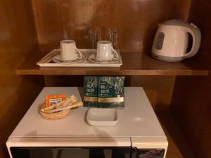 a small refrigerator with two plates and cups on a shelf at Hotel HANAMIZUKI-Adult Only in Otaru