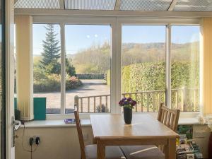 a dining room with a table and a large window at Thistle Dubh in Drumnadrochit