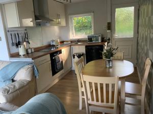 cocina con mesa de madera, mesa y sillas en CRIB GOCH HOLIDAY CABIN SNOWDONIA en Caernarfon