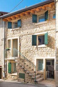 a stone house with stairs and green shutters at Ca' Del Jago Sole Luna apartment in Negrar