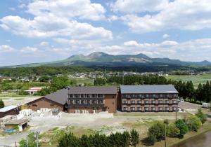 a large building with mountains in the background at Aso Hakuun Sanso in Aso