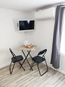 聖熱爾韋的住宿－Les Gones en Vendée，一张带两把椅子的小桌子和墙上的一台电视