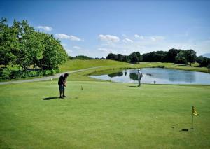 dos personas jugando al golf en un campo de golf con un estanque en Artzamendi, LA RHUNE, 4 Chambres 155 m2, en Ustaritz