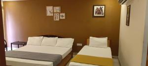 2 camas en una habitación con fotos en la pared en Sridhar Lodge en Srikalahasti