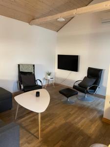 ein Wohnzimmer mit 2 Stühlen, einem Tisch und einem TV in der Unterkunft Dejlig lejlighed in Svinninge