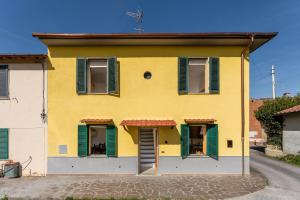 una casa amarilla con persianas verdes en una calle en Enza's Petite Maison, en Santa Croce sull'Arno
