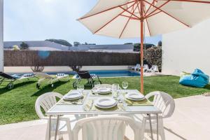 une table blanche avec des chaises et un parasol dans l'établissement Villa do Casalinho, à Sesimbra