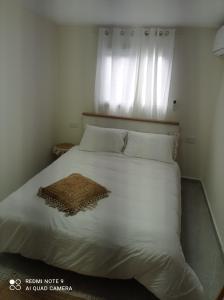 a bedroom with a white bed with a window at פסגת הדרור in Shelomi