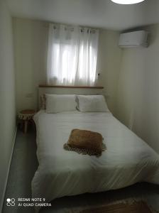 a bedroom with a large white bed with a window at פסגת הדרור in Shelomi