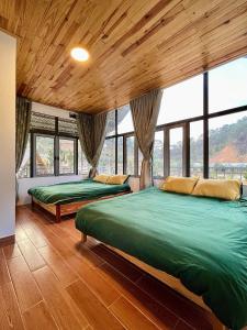 two beds in a room with wooden ceilings and windows at Đồi Lát Homestay in Ấp An Kroët
