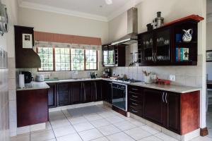 a kitchen with dark wood cabinets and a sink and a counter at Porterfield Guest House, Champagne Valley in Champagne Valley