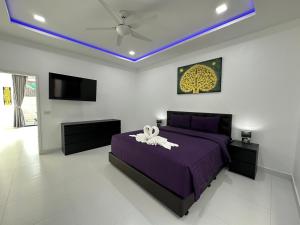 a bedroom with a purple bed and a tv at CHATEAU DALE POOL VILLA 176 nearby WALKING STREET in Pattaya South